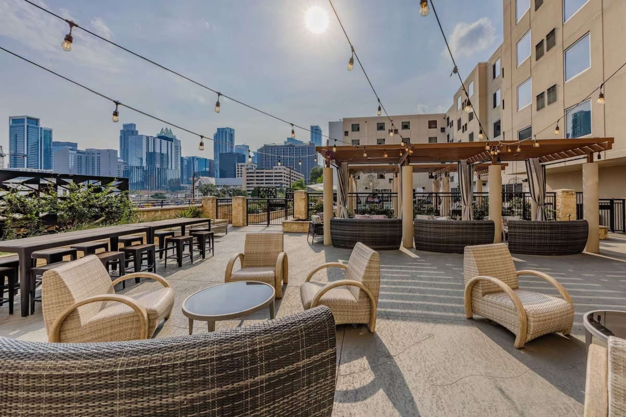 An outdoor seating area with wicker furniture, a pergola, and a city skyline view.