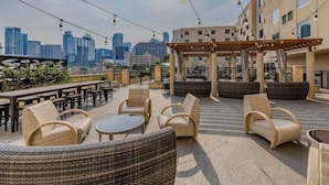 An outdoor seating area with wicker furniture, a pergola, and a city skyline view. - Near Texas Capitol + Rooftop Pool. Bar. Dining. (Austin)