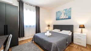 Un dormitorio ordenado con cama, mesitas de noche, un cuadro y un armario.