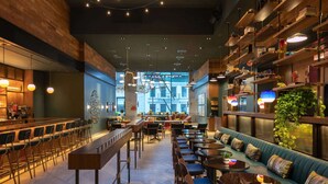 Een moderne bar met hoge krukken, een lange toonbank en een zithoek met tafels en een bank.