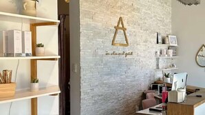 A reception area with a white brick wall, a wooden reception desk, and shelves with various items.