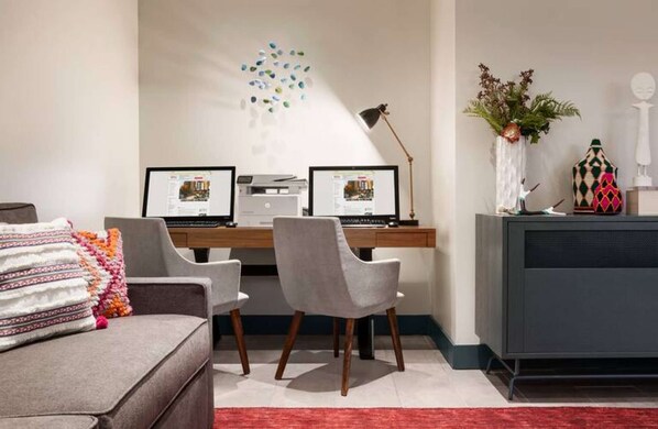 Un espace de bureau moderne comprenant deux bureaux, un canapé et une plante décorative.