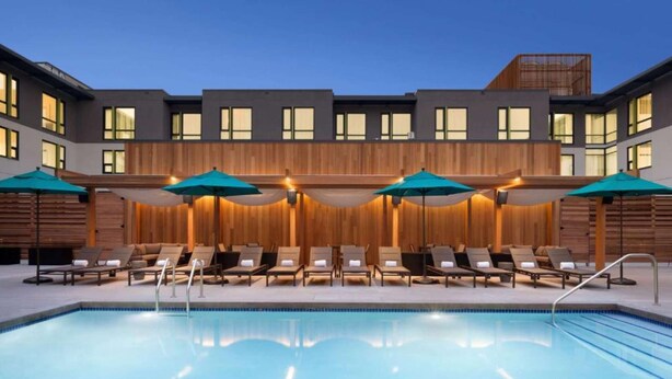 Un hôtel moderne doté d’une piscine, de chaises longues et de parasols.