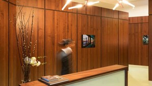 A reception area with wooden paneling, a vase with branches and flowers, and a framed picture on the wall. - Moments Away From The Iconic Manhattan Bridge (New York)