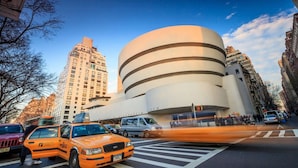 Un edificio moderno de diseño circular único, situado en un entorno urbano con edificios altos a su alrededor.