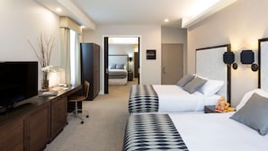 Una habitación de hotel con televisión, escritorio y dos camas.