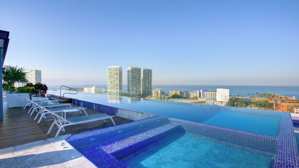 A rooftop infinity pool with lounge chairs and a city view. - Stunning Ocean+Marina Views Rooftop Infinity Pool (Puerto Vallarta)