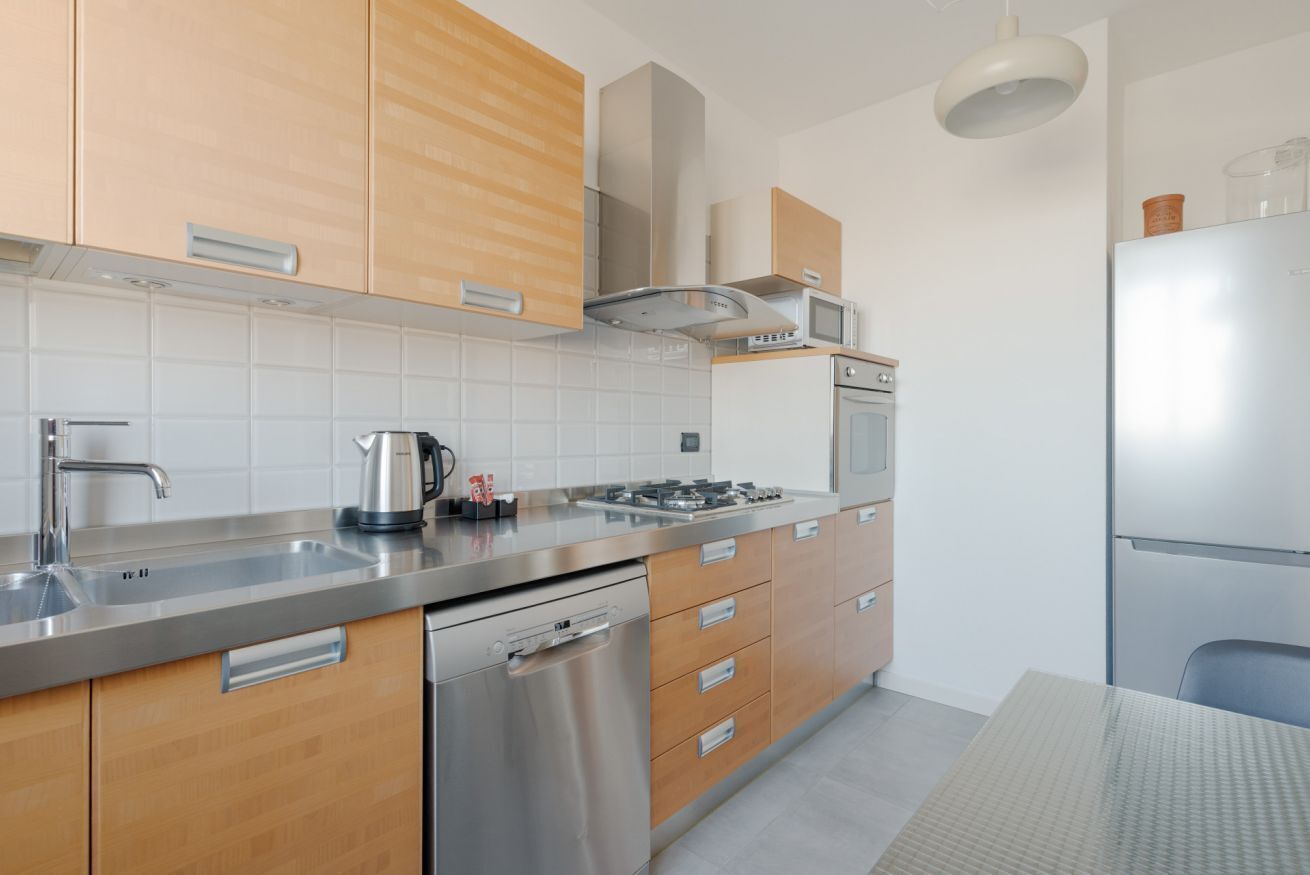 Une cuisine moderne dotée d’appareils électroménagers en acier inoxydable, de meubles en bois et d’un four encastré.