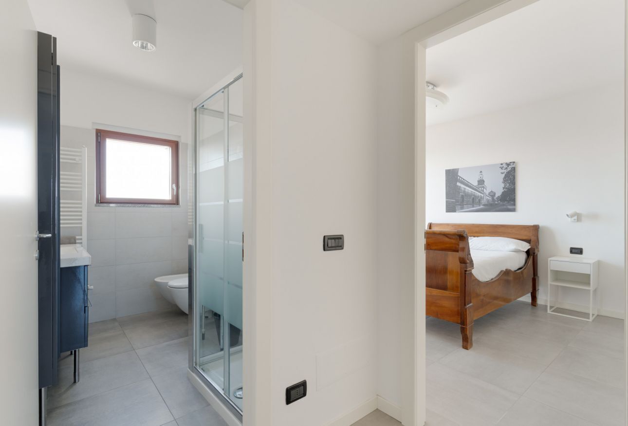 Une chambre à coucher moderne avec un lit en bois, une table de chevet blanche et une petite commode blanche.