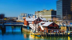 A ship docked at a pier with a building in the background. - In The Heart of Boston’s Seaport + Rooftop Bar (Boston)
