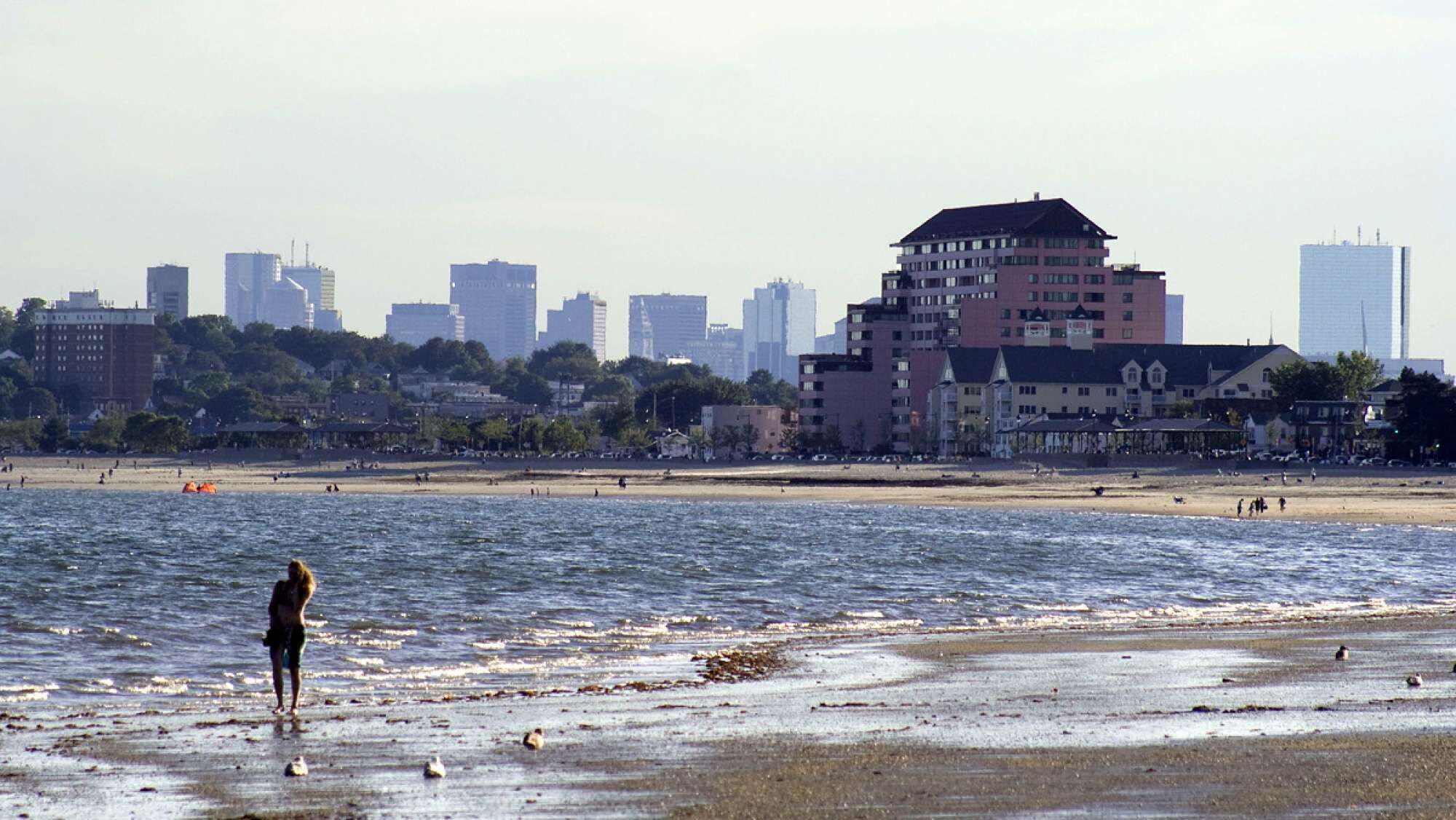 Une plage avec la silhouette d’une ville en arrière-plan.