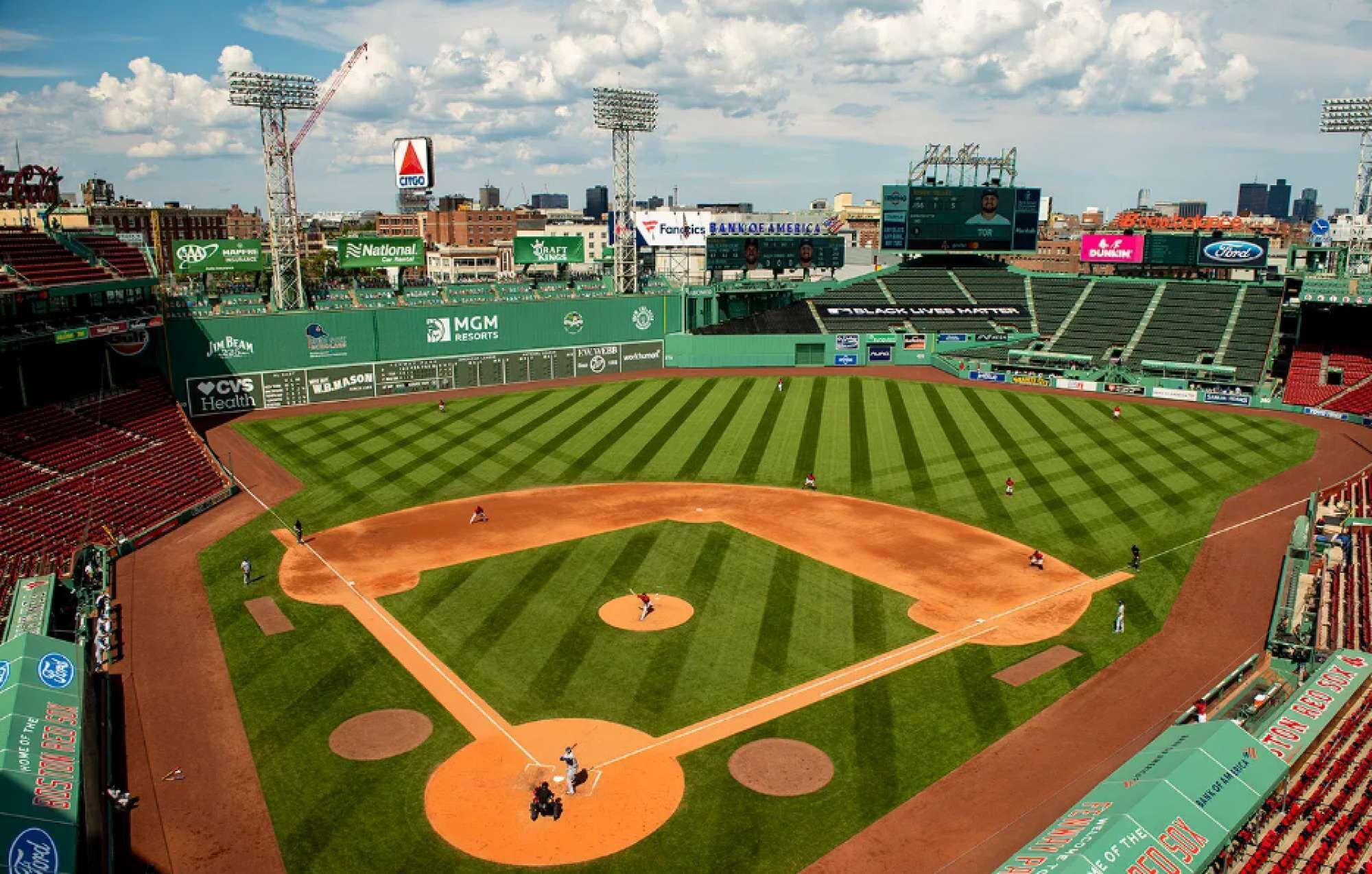 A baseball stadium with multiple seating sections, a large scoreboard, and various advertisements.