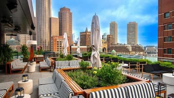 Une terrasse sur le toit, dotée d’un espace extérieur aménagé, de verdure et offrant une vue panoramique sur la ville.