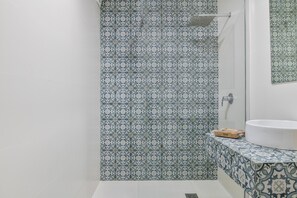 Un baño con baldosas estampadas, un lavabo blanco y una zona de ducha.
