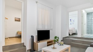 Een moderne woonkamer met een flatscreen televisie, een klein tafeltje en een trap naar een andere kamer.