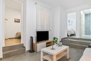 Ein modernes Wohnzimmer mit Fernseher, einem kleinen Tisch und einer Treppe, die in einen anderen Raum führt.