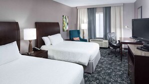 A hotel room with two beds, a desk, a chair, a TV, and a window with curtains. - Steps to Fountain Walk + On-site Dining. Pool. Gym (Novi)