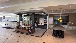 A spacious lobby with a food kiosk, a seating area, and a view of the outside. - Steps to Fountain Walk + On-site Dining. Pool. Gym (Novi)