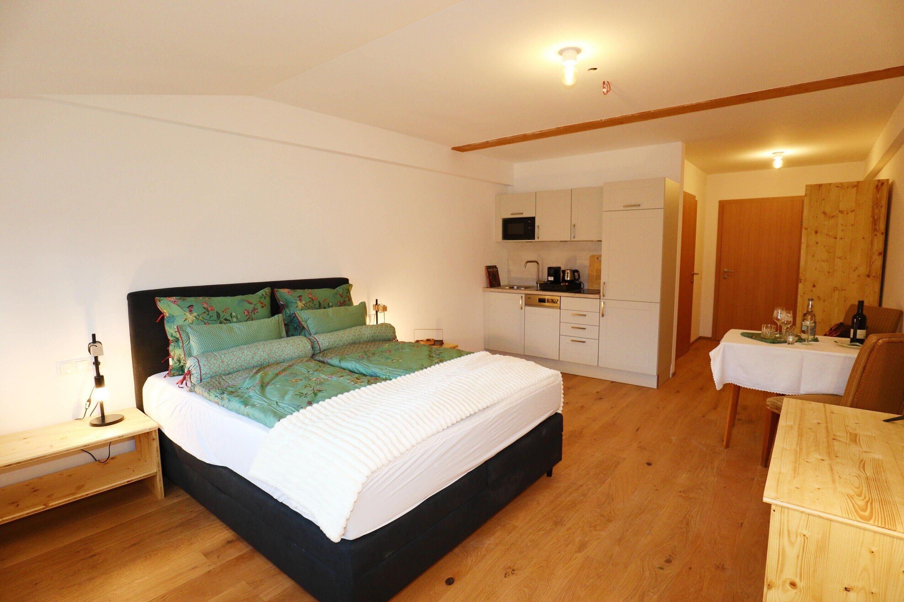 A bedroom with a bed, bedside table, and a small desk.