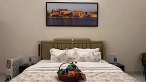 Ett hotellrum med en säng, en sänggavel, en tavla med en stadsbild som hänger på väggen, ett nattduksbord med en vattenflaska och en korg med snacks.