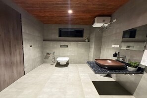 Ein modernes Badezimmer mit Holzboden, einer weißen Toilette, einem braunen Waschbecken und einem kleinen Fenster.