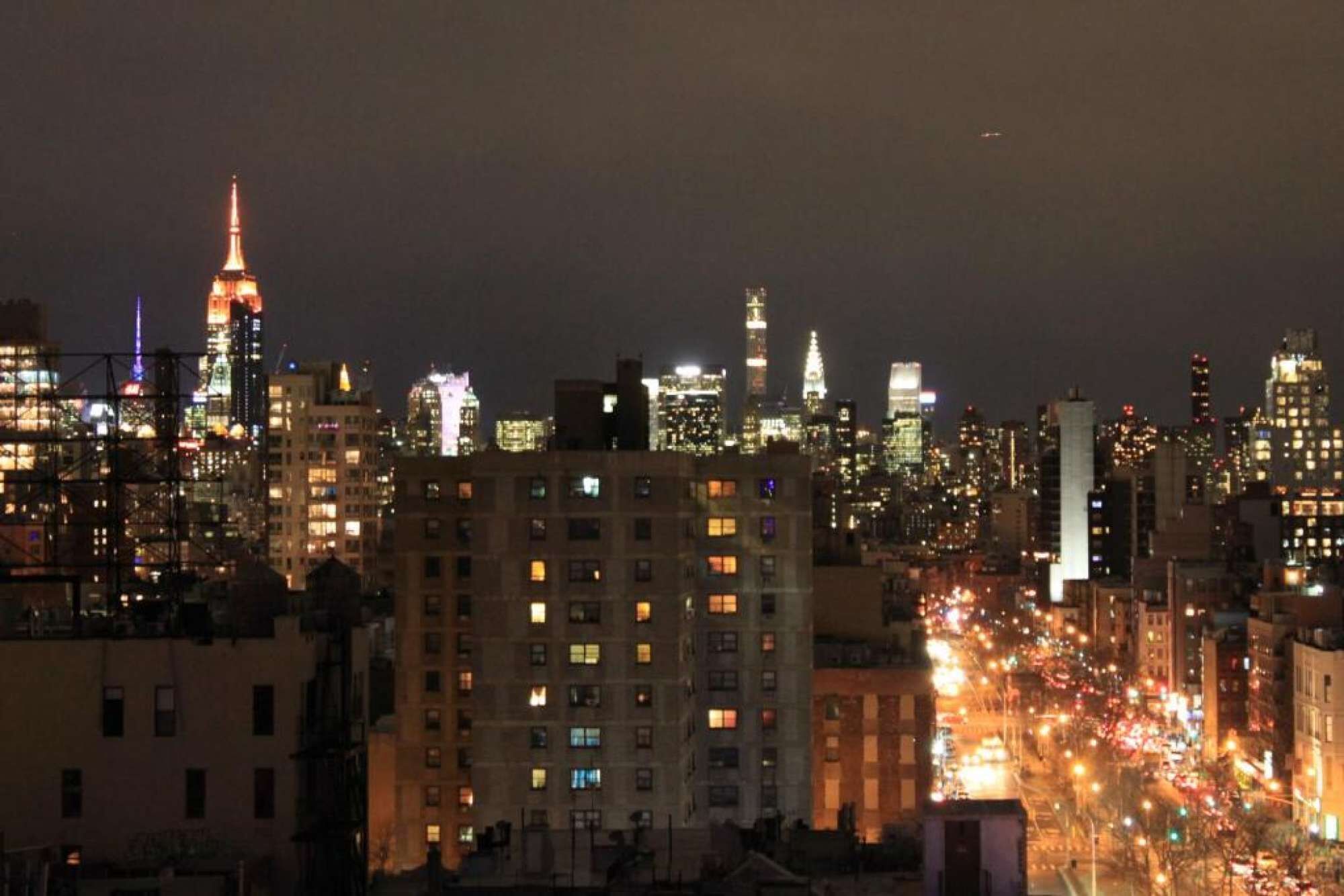 A nighttime cityscape with illuminated buildings and a busy street.