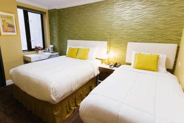 Two beds with yellow accents beside patterned green wall.