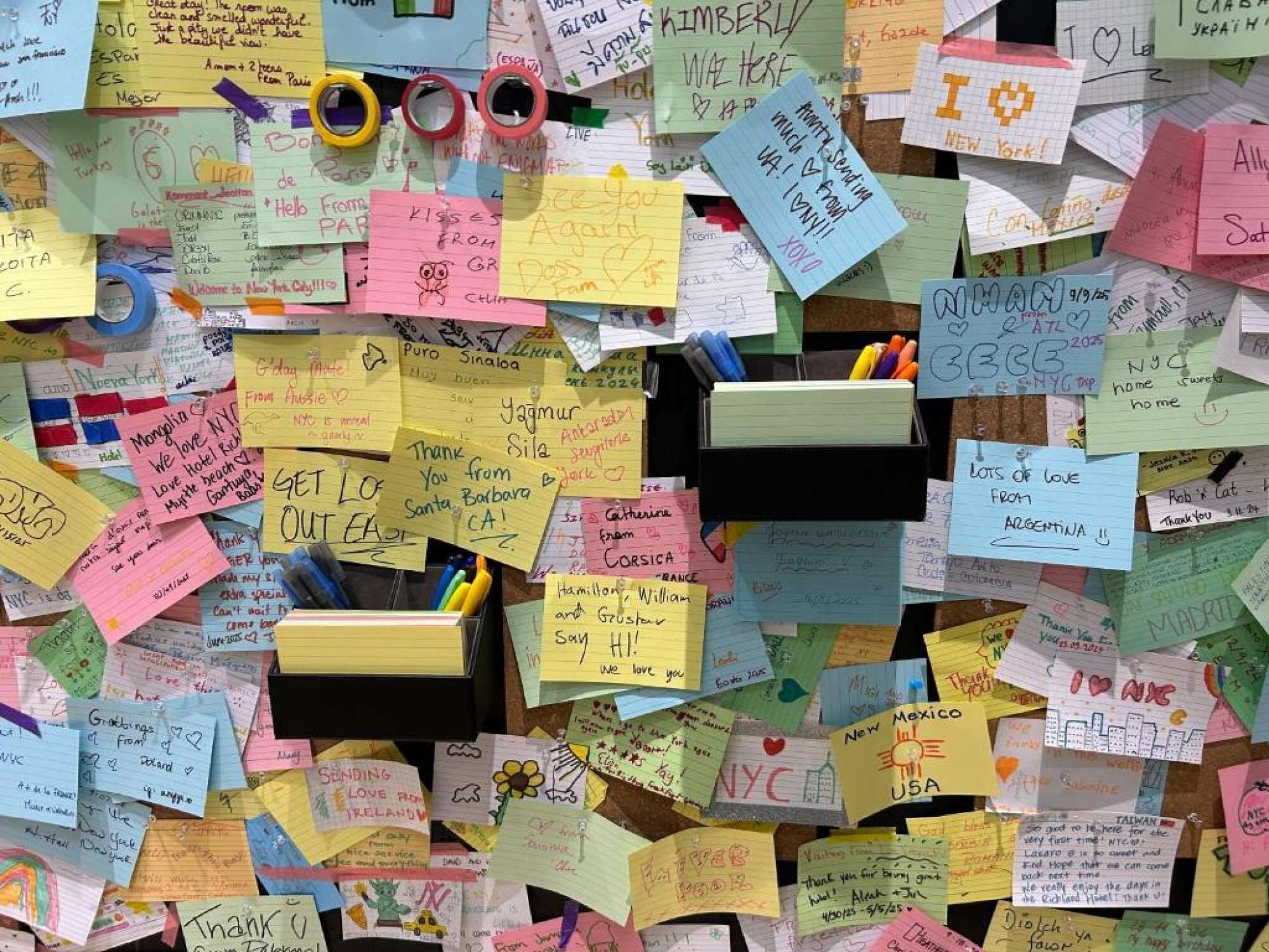 Wall covered with colorful guest notes, drawings, and messages from afar.