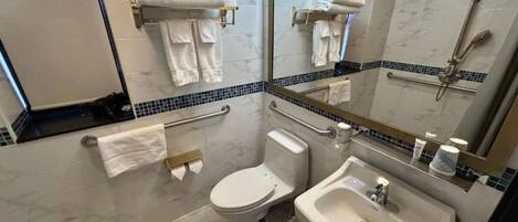 Bathroom with large mirror, towels, tiled walls, and accessible fixtures.