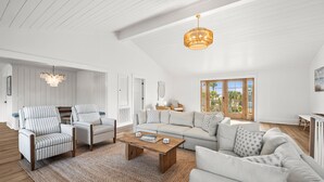 A spacious living area with a high ceiling, a wooden coffee table, striped armchairs, a sofa, and a hanging light fixture. - 798 Marlin Drive (Saint Helena Island)