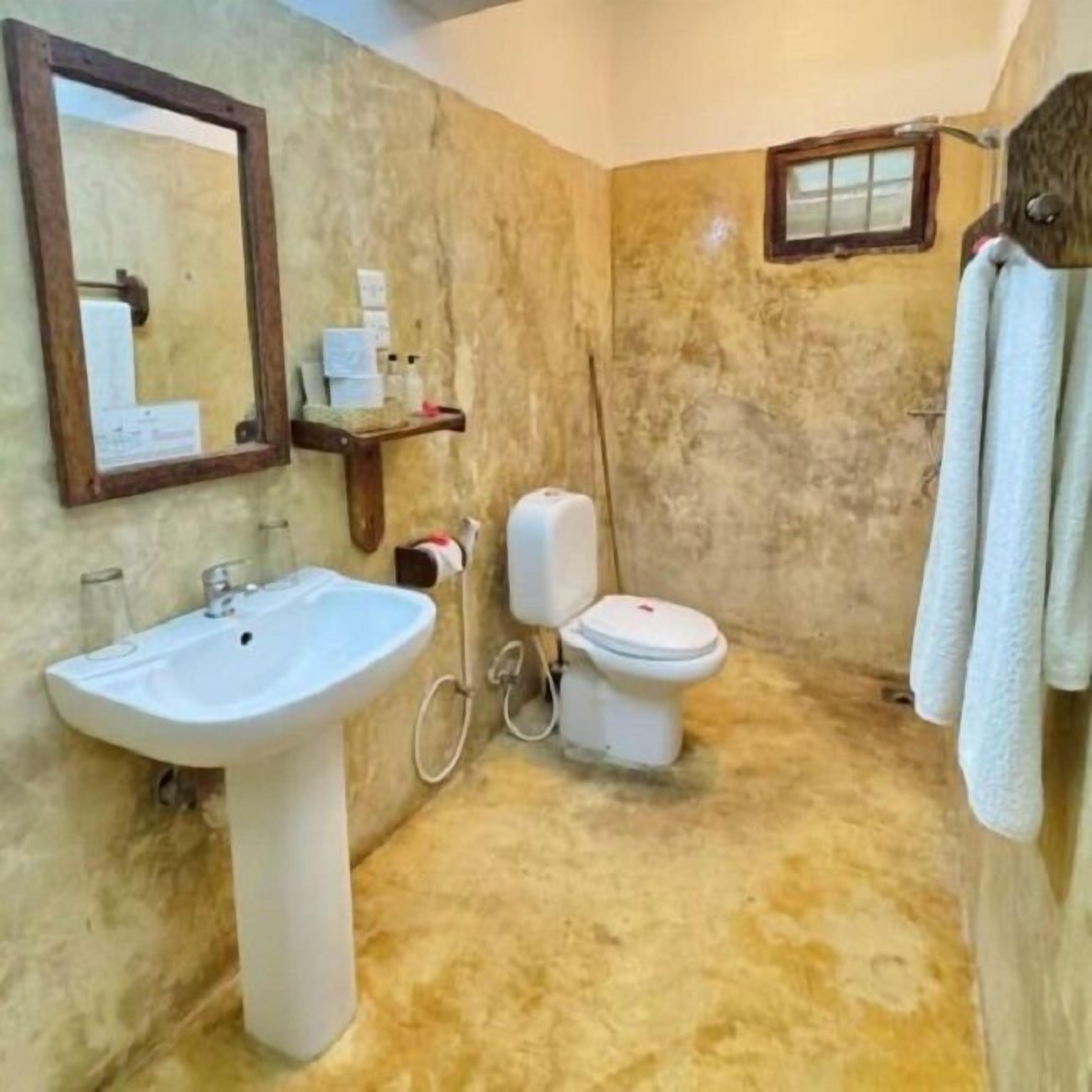A bathroom with a sink, toilet, and mirror.