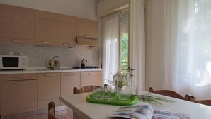 Una cocina moderna con armarios de madera, un microondas y un comedor con una mesa dispuesta para dos personas.