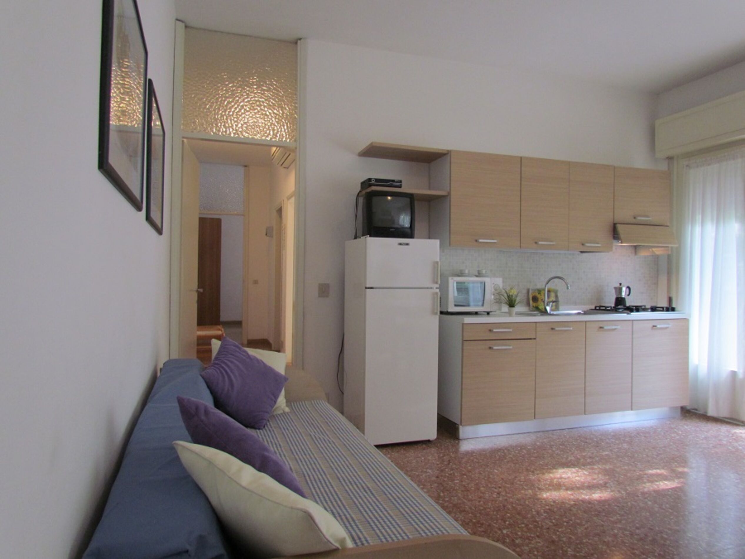 A compact living space with a kitchenette, a sofa with cushions, and a small dining area.