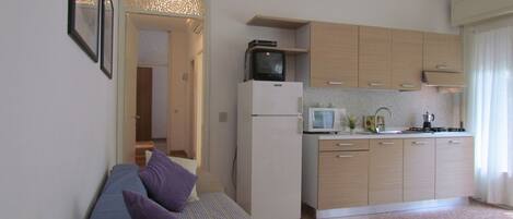 A compact living space with a kitchenette, a sofa with cushions, and a small dining area.