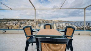 Una terrazza con tavolo e sedie, vista sulla città costiera.