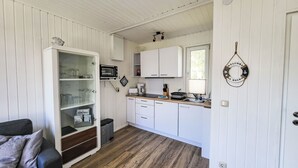 A compact kitchen with white cabinets, a microwave, a coffee maker, and a sink. - Bungalow 33 by Interhome (Middelhagen - Insel Rügen)