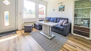 A modern living room with a grey sofa, a coffee table, and a glass cabinet with decorative items. - Bungalow 33 by Interhome (Middelhagen - Insel Rügen)