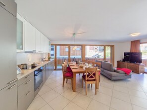 A modern kitchen with a dining area, a sofa, and a TV. - Perrine by Interhome (Saas-Fee)