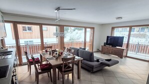 A spacious living area with a dining table, sofa, and TV. - Perrine by Interhome (Saas-Fee)