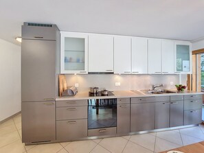 A modern kitchen with stainless steel appliances, white cabinets, and a built-in oven. - Perrine by Interhome (Saas-Fee)