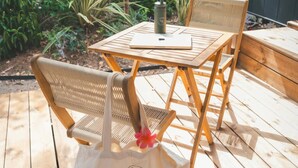 A wooden deck with wicker chairs and a table, a white tote bag with 'HoloCamp' logo, and a metal water bottle. - Tiny Holiday Home in Sant Salvador for Couple (El Vendrell)