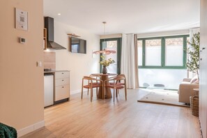 Een moderne keuken met een eethoek, een televisie boven de counter en een groot raam met gordijnen.