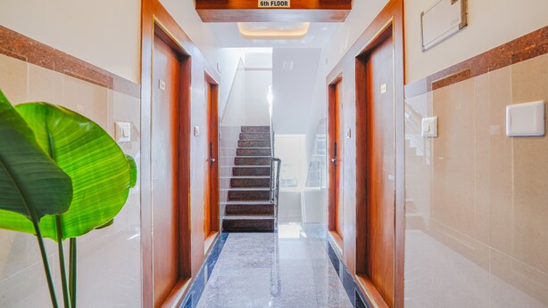 Un couloir d’hôtel avec un sol en marbre, des portes en bois et un escalier menant au sixième étage.