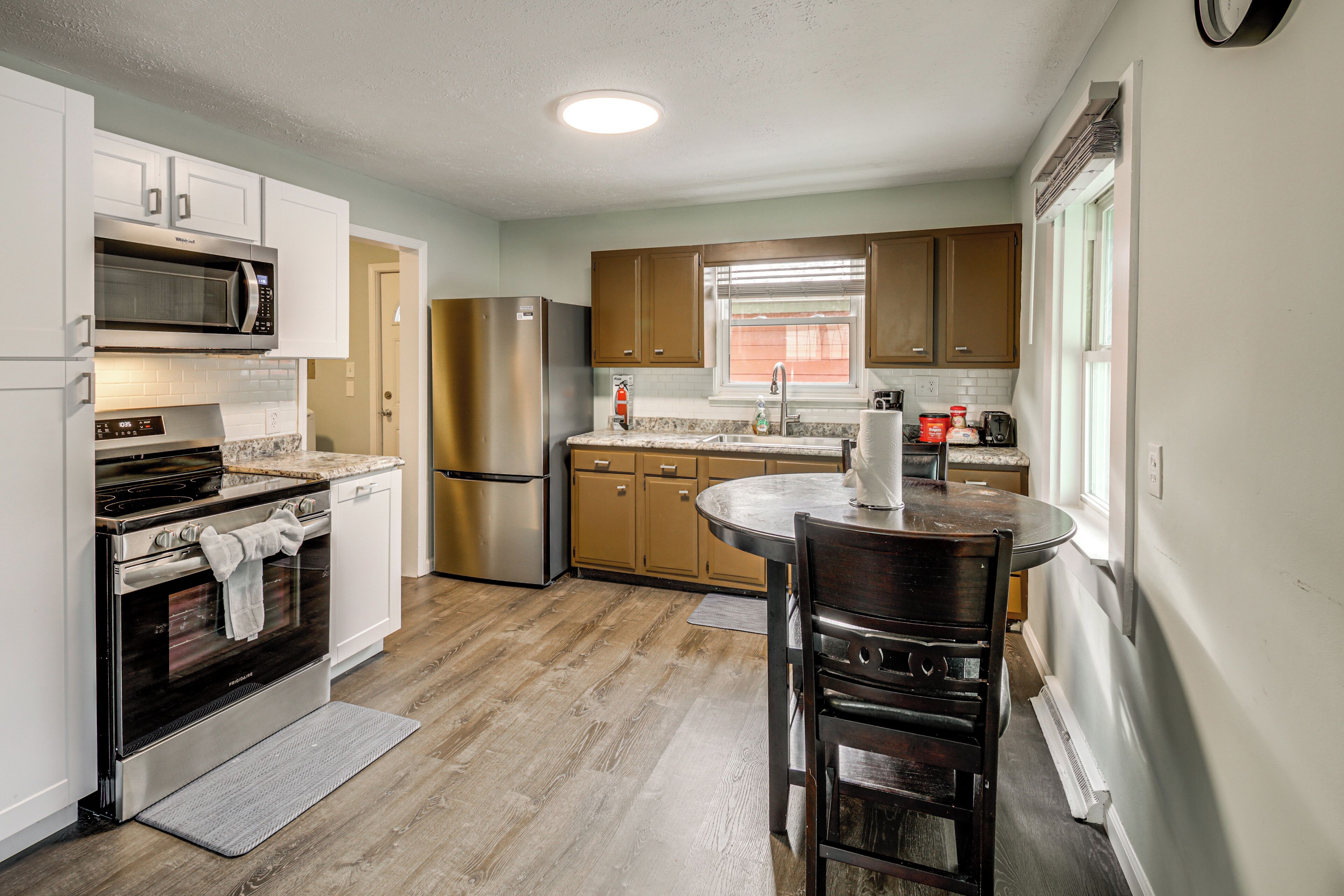 A modern kitchen with stainless steel appliances, wooden cabinets, and a round dining table.