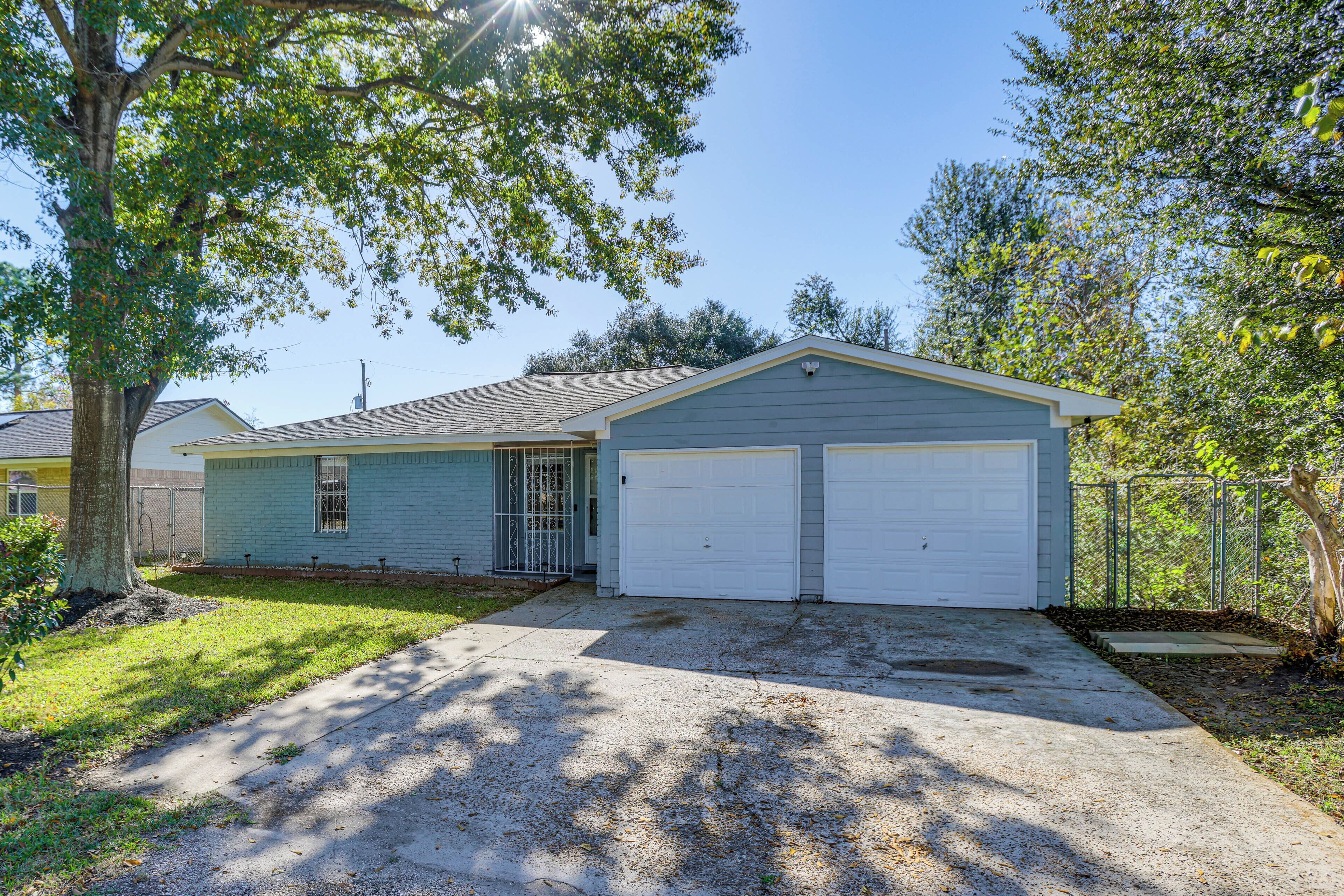 A single-story house with a garage, a front yard, and a tree.