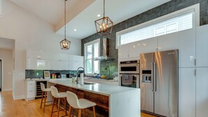 Una cocina moderna con una isla grande, electrodomésticos de acero inoxidable y taburetes de bar de madera.
