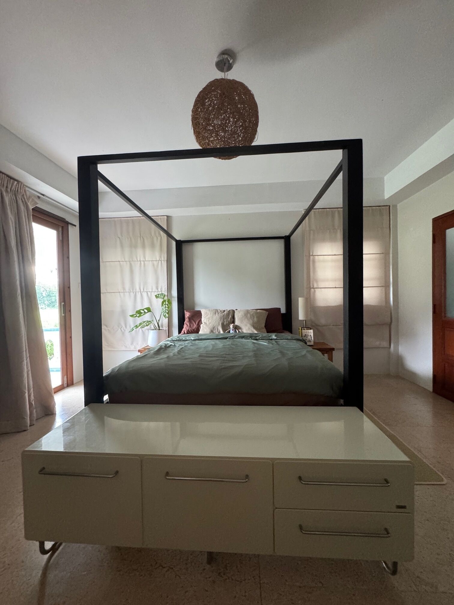 A four-poster bed with a canopy, a bedside table, and a nightstand.