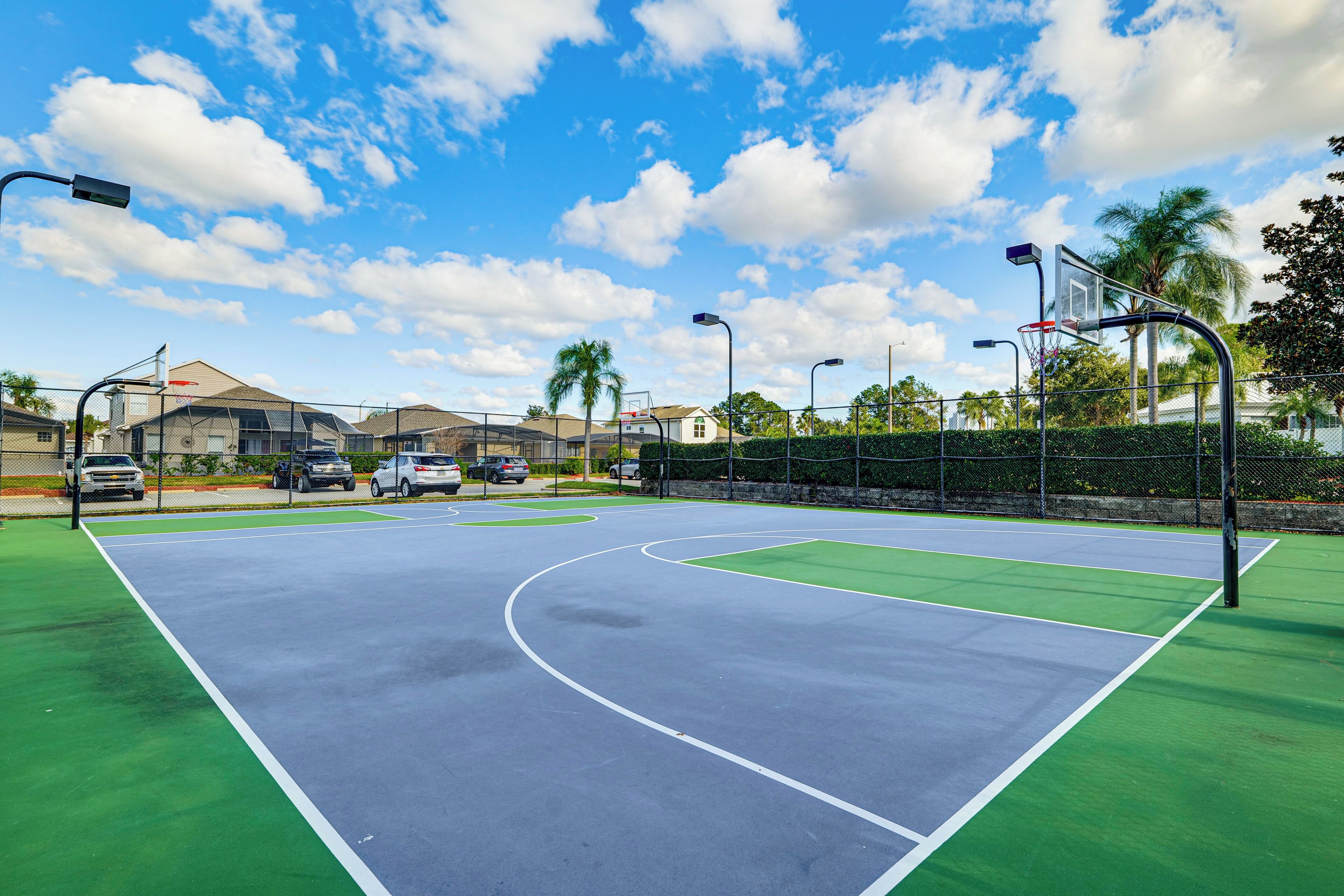An outdoor basketball court with a clear sky and palm trees.