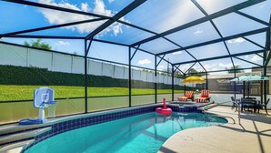 A covered swimming pool with a basketball hoop, lounge chairs, and umbrellas. - Resort Perks! Family Home 4 Mi to Disney World (Kissimmee)