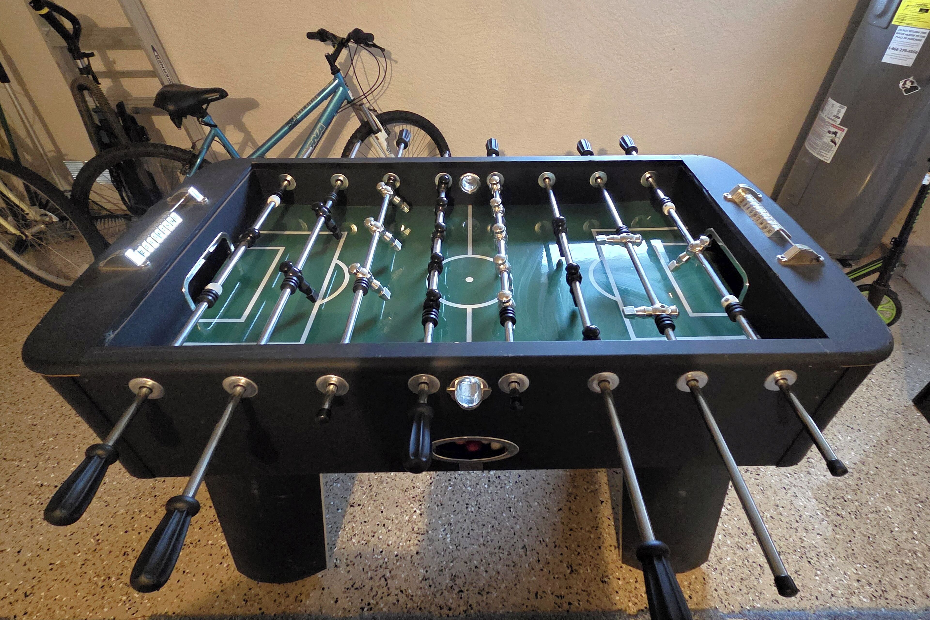 A foosball table with multiple rods and a netted playing area.